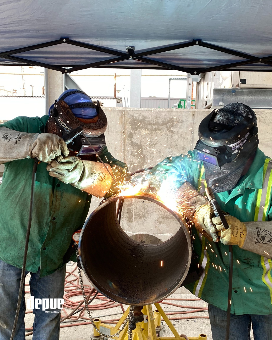 Two certified pipe welders performing code weld on industrial pipe with visible sparks during fabrication process at DePue Mechanical