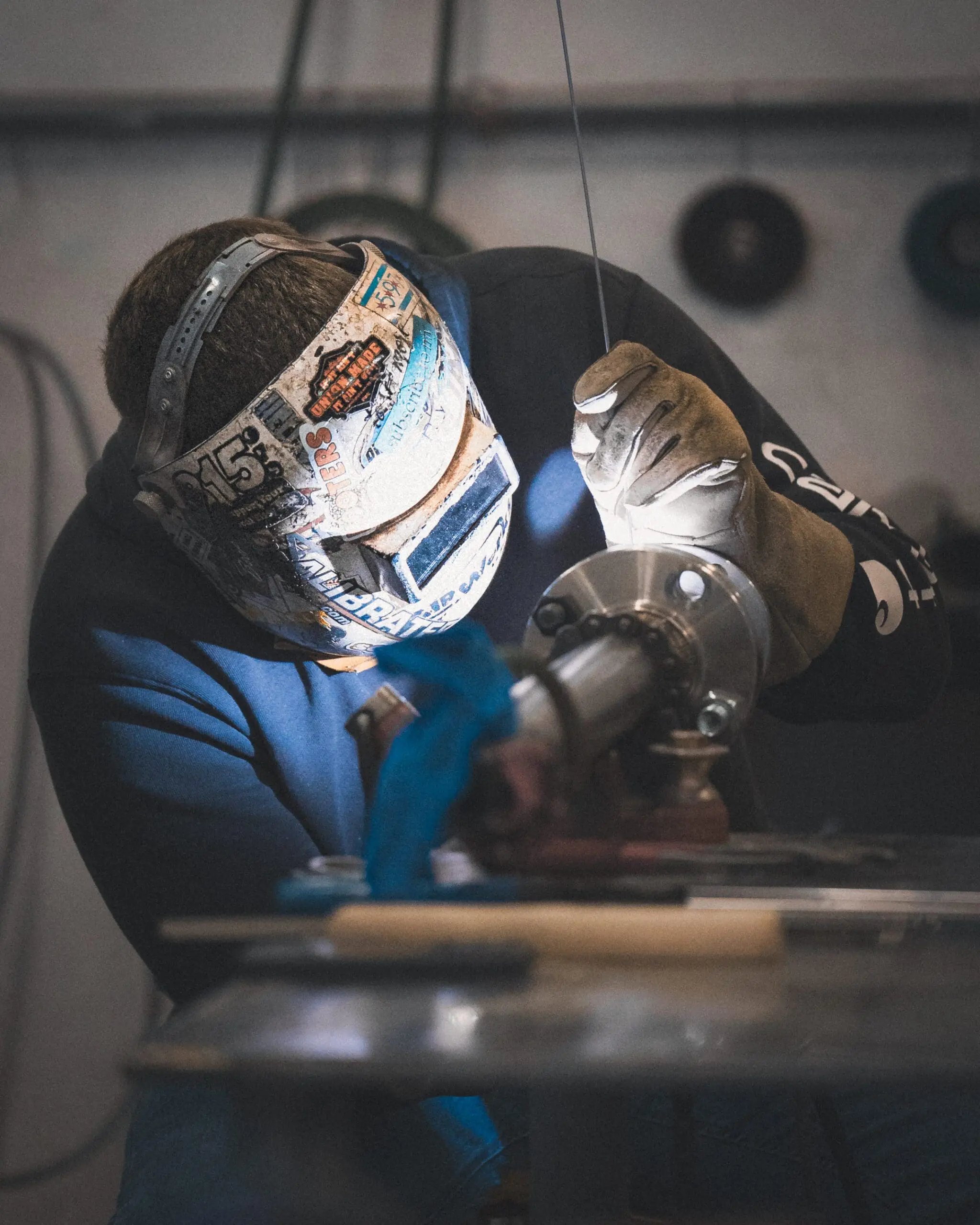 Welder working on a pipe fitting in a fabrication area
