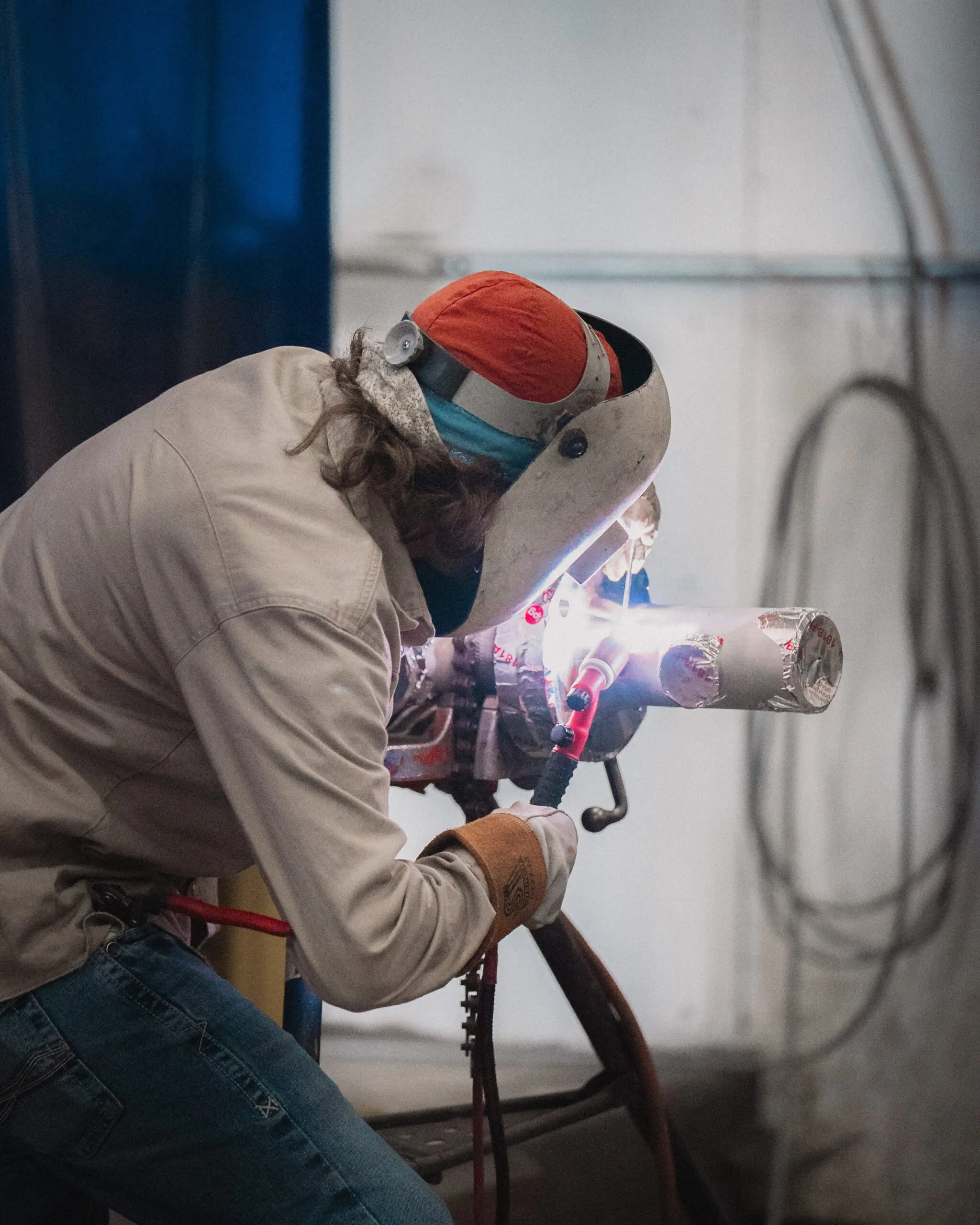 ASME-certified welder performing precision weld on pipe joint, demonstrating certified code welding in an industrial facility environment.