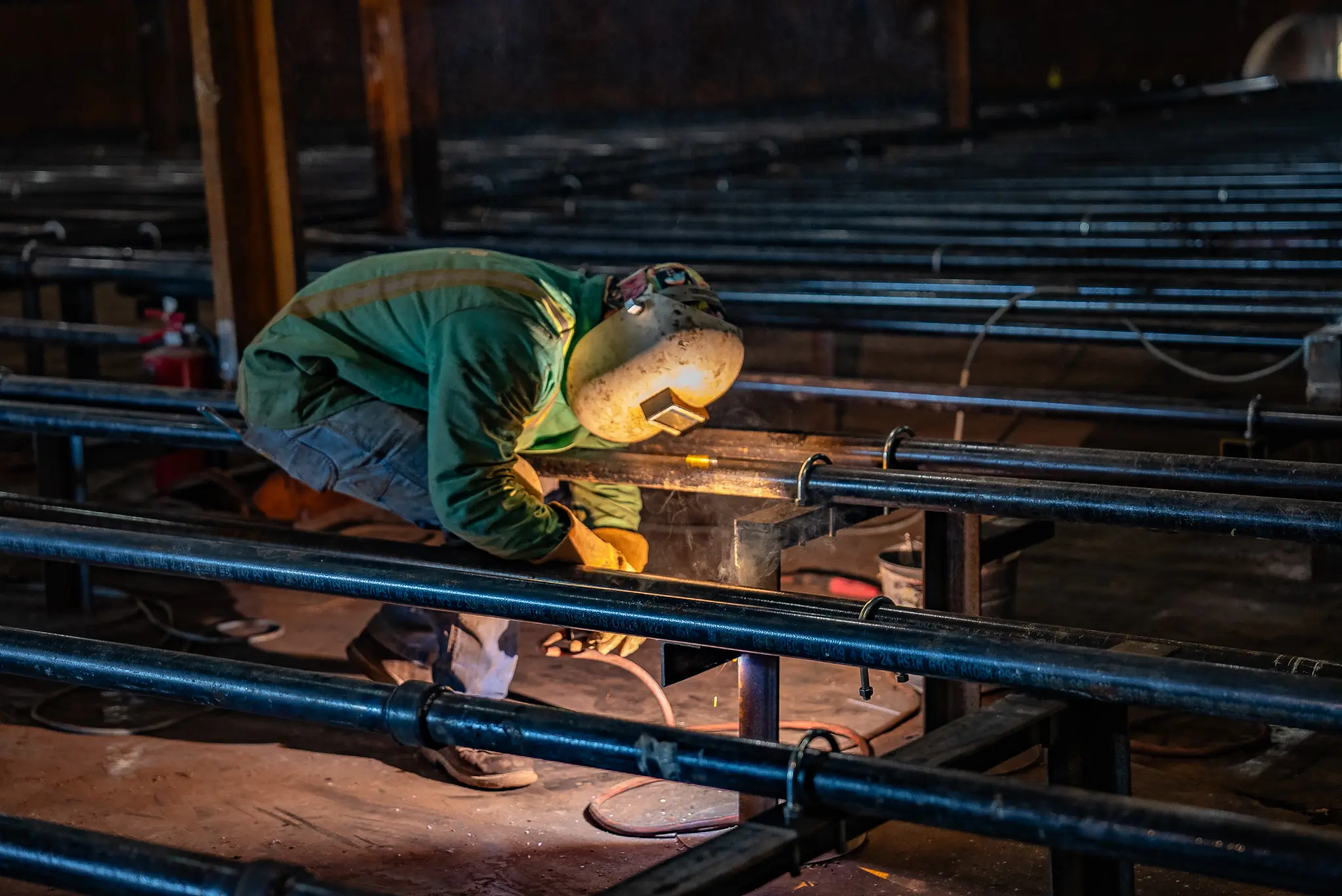 Welder fabricating coil lines during industrial piping installation inside a facility