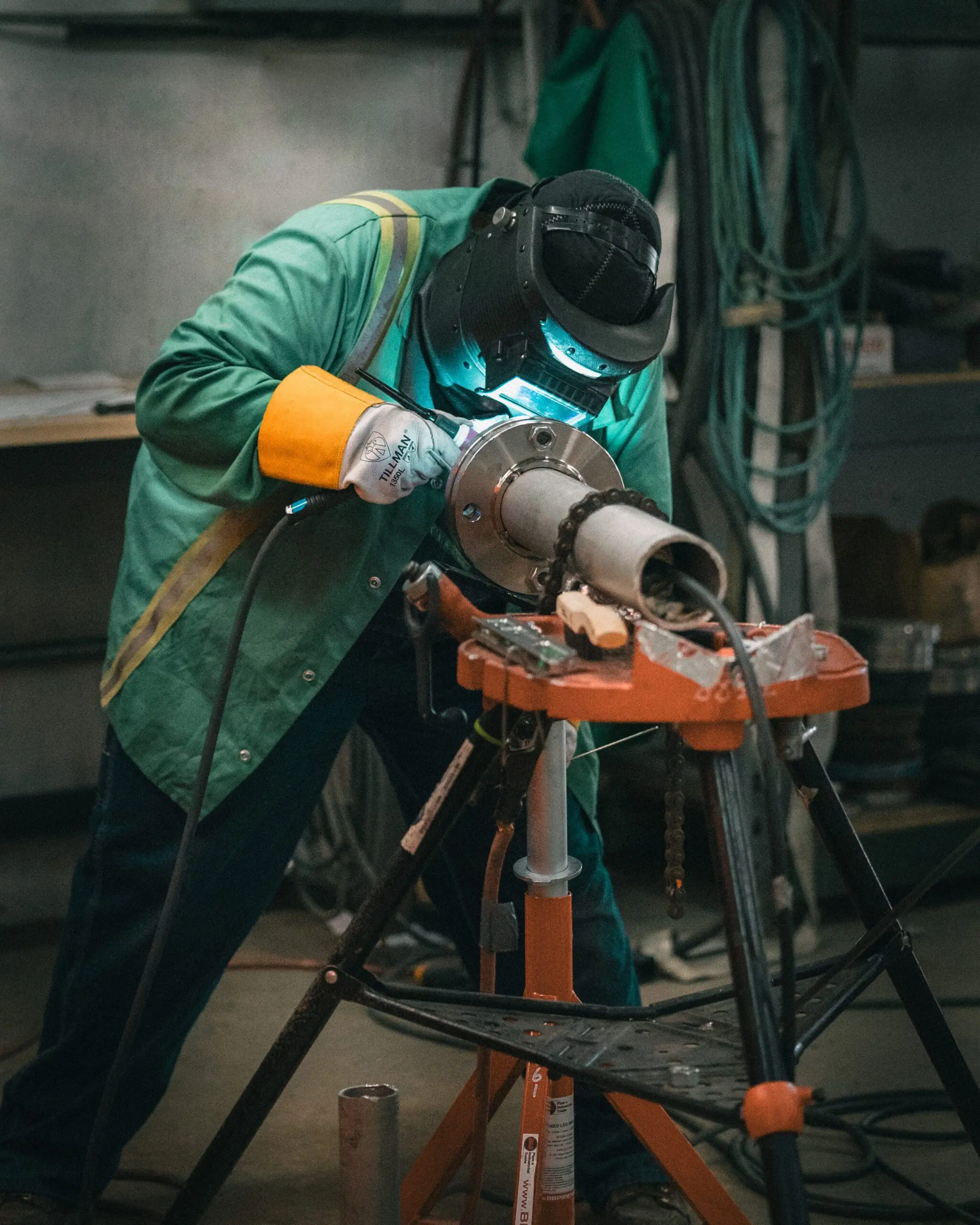 Pipefitter welding stainless steel process piping flange on vise stand during prefabrication
