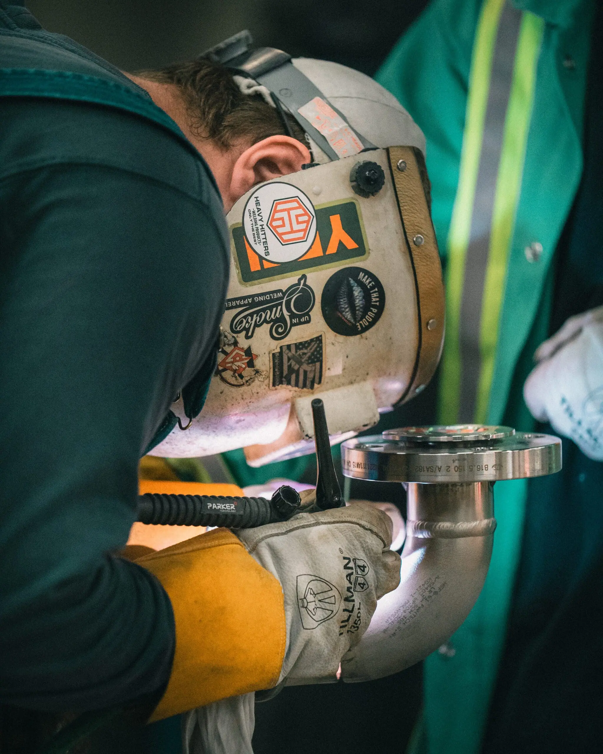 Certified pipe welder performing precision TIG weld on stainless steel elbow joint for industrial piping system