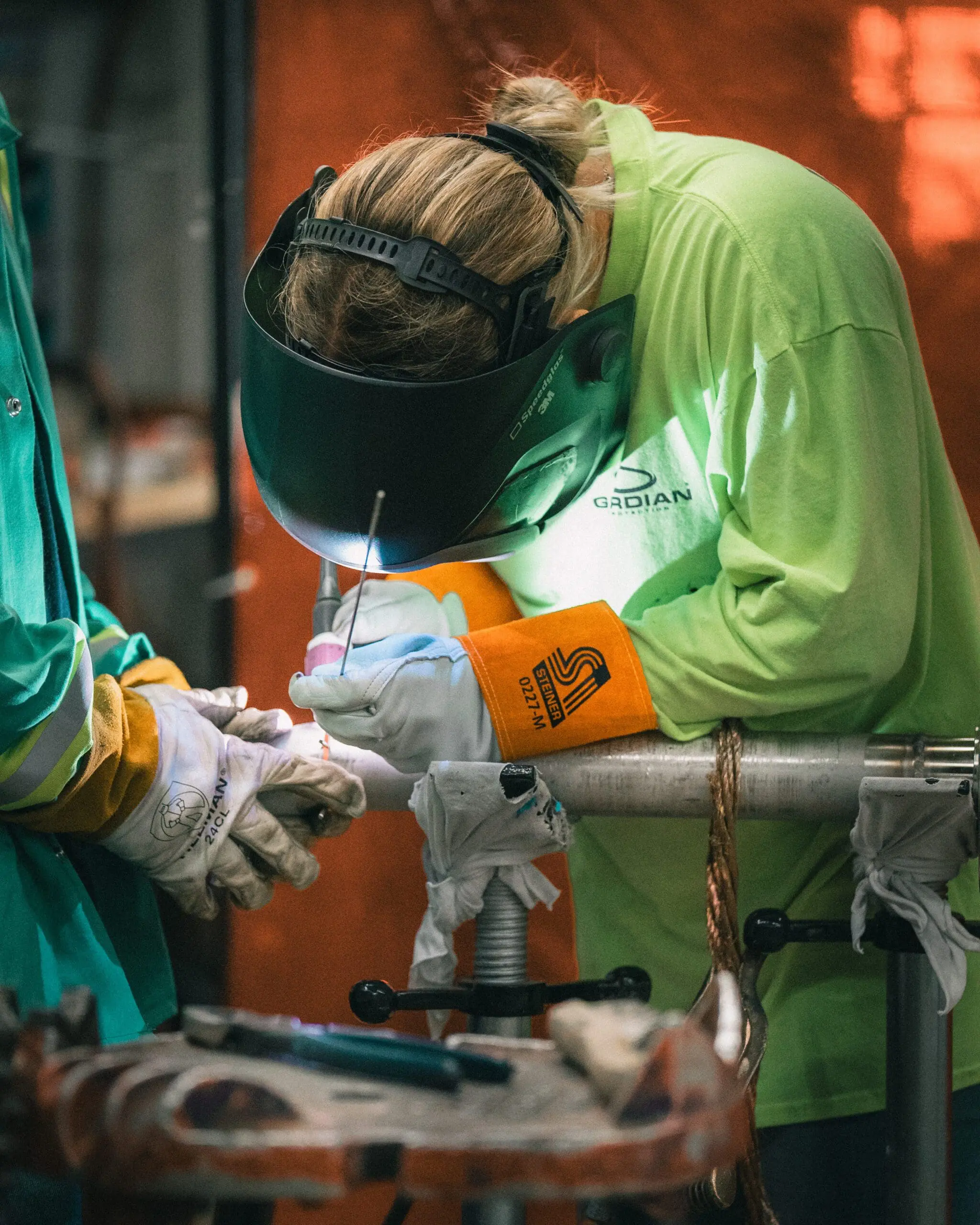 Welder working on a pipe connection inside an industrial facility