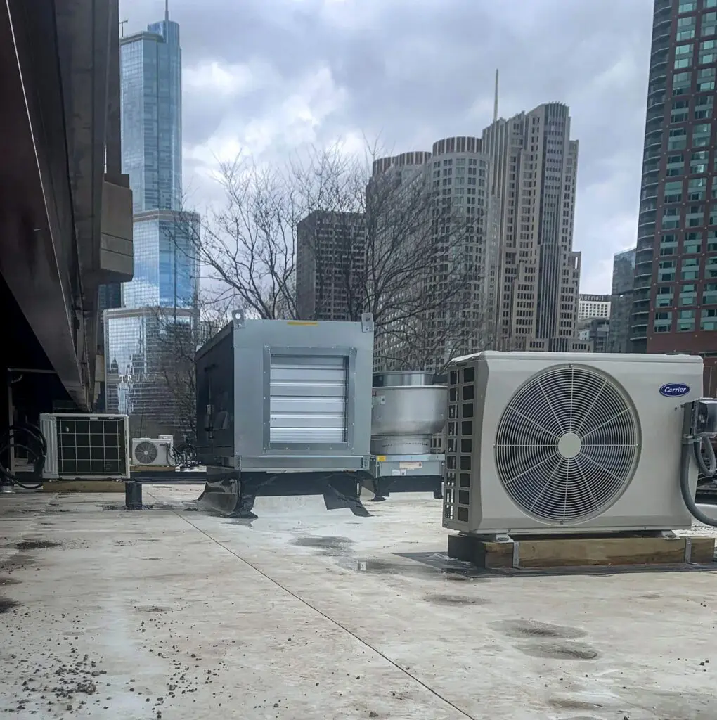 Rooftop HVAC unit and commercial split system condenser installed on Chicago building by HVAC mechanical contractors during HVAC maintenance for commercial facilities
