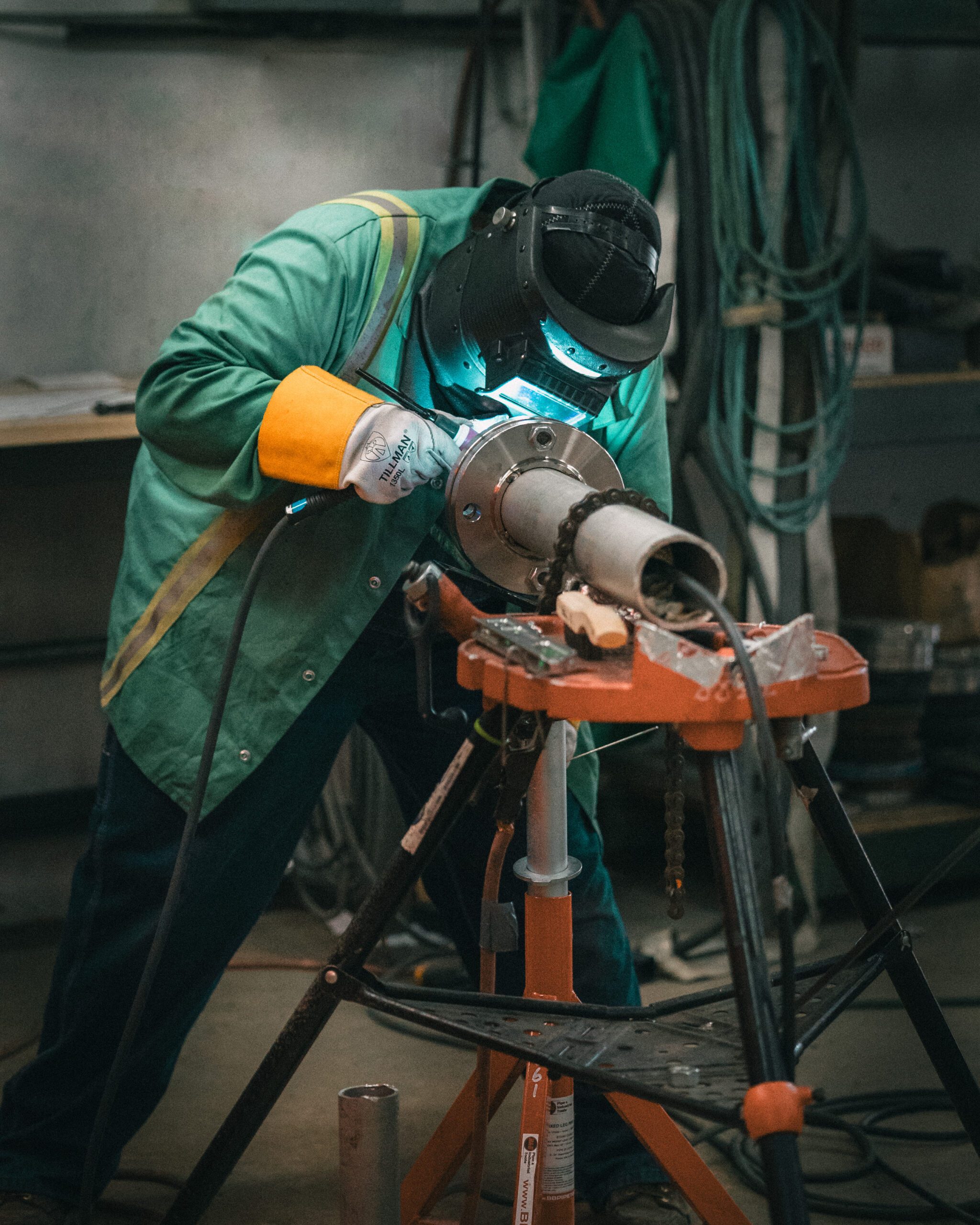 Pipefitter welding stainless steel process piping flange on vise stand during prefabrication