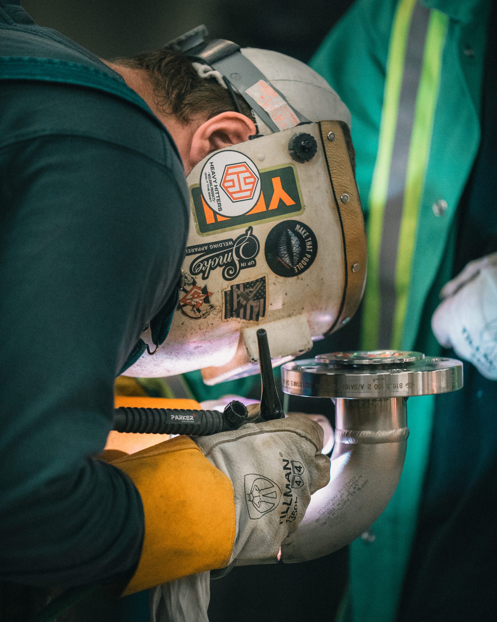Certified pipe welder performing precision TIG weld on stainless steel elbow joint for industrial piping system