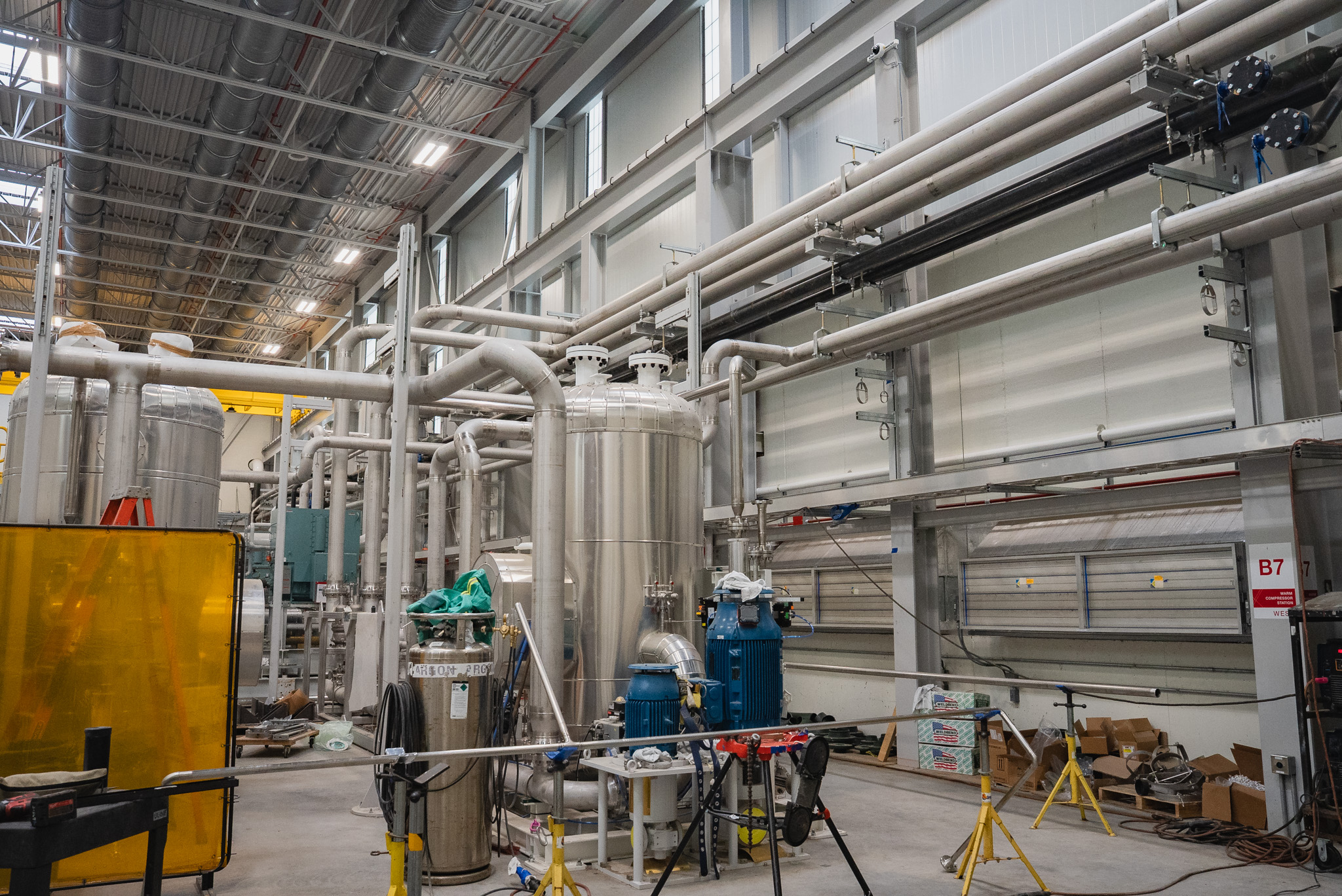 Interior industrial piping installed along a facility wall and ceiling