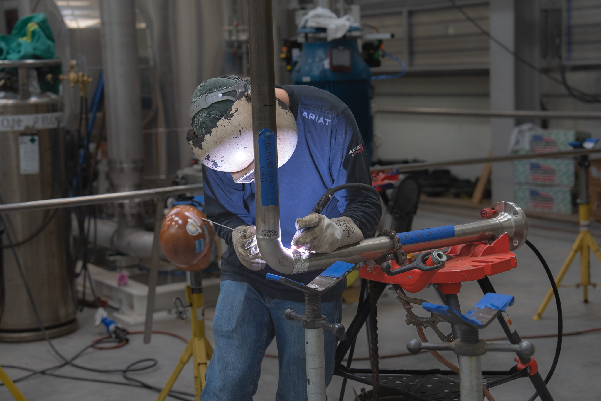 Certified welder performing industrial pipe welding in a fabrication shop