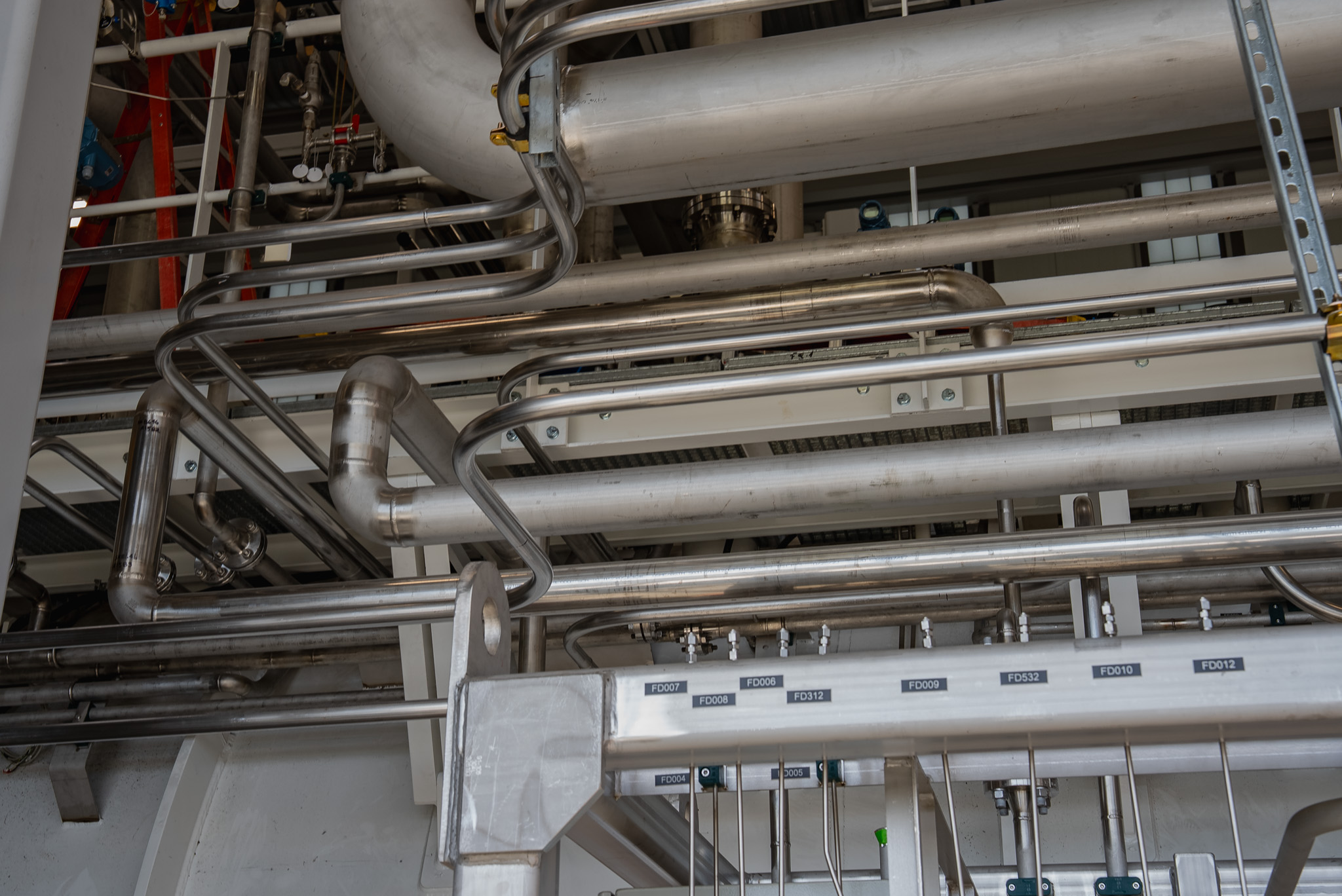 Overhead piping installed along an interior industrial facility wall